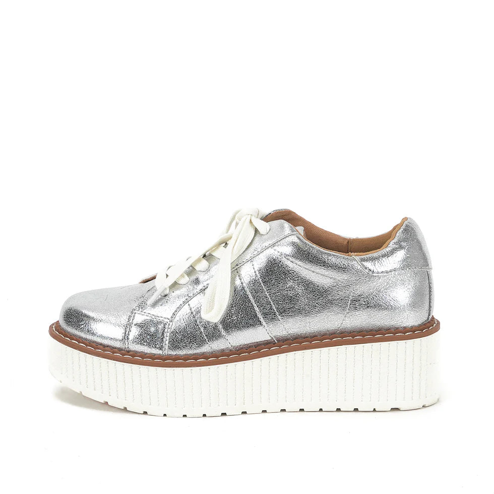 Metallic silver lace-up flatform sneaker with textured white platform sole photographed on a white background.