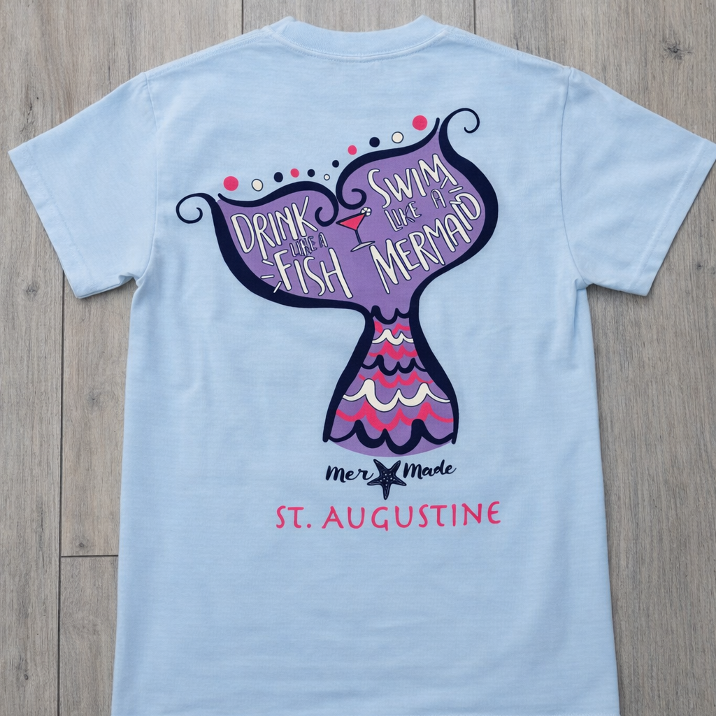 Back of light blue St. Augustine t-shirt with mermaid tail graphic and “Drink Like a Fish, Swim Like a Mermaid” text in pink, purple, and navy.