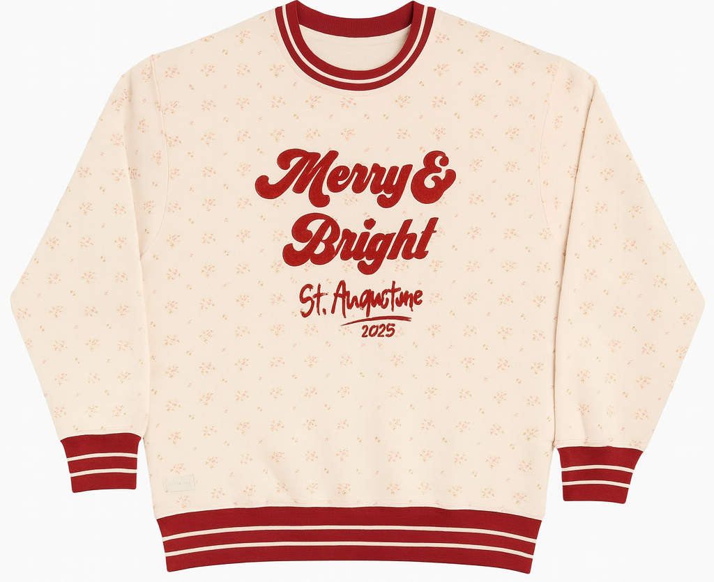 Light pink holiday sweatshirt with red “Merry & Bright St. Augustine 2025” embroidery, red striped cuffs and collar, and a subtle floral pattern—festive cozy style perfect for the holidays.