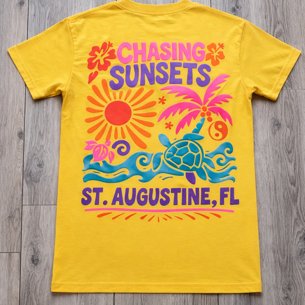 Back of yellow St. Augustine t-shirt with colorful “Chasing Sunsets” graphic featuring a sun, palm tree, waves, sea turtle, and St. Augustine, FL text.