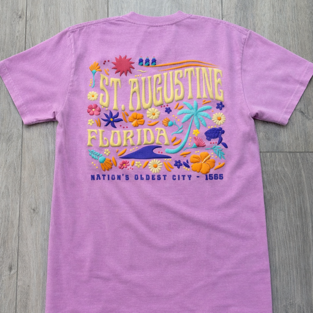 Back of lavender St. Augustine Florida t-shirt with colorful tropical floral design, palm tree, sea turtle, and “Nation’s Oldest City - 1565” text.