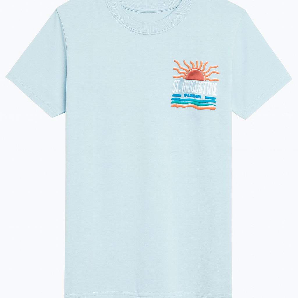 Light blue St. Augustine Florida T-shirt featuring a bold retro sun and ocean waves design in orange, teal, and white. Soft cotton fabric with vibrant raised print celebrating Florida’s coastal charm — exclusive to Artsy Abode.