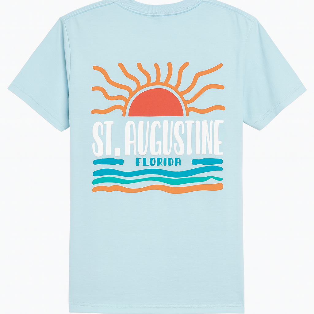 Light blue St. Augustine Florida T-shirt featuring a bold retro sun and ocean waves design in orange, teal, and white. Soft cotton fabric with vibrant raised print celebrating Florida’s coastal charm — exclusive to Artsy Abode.