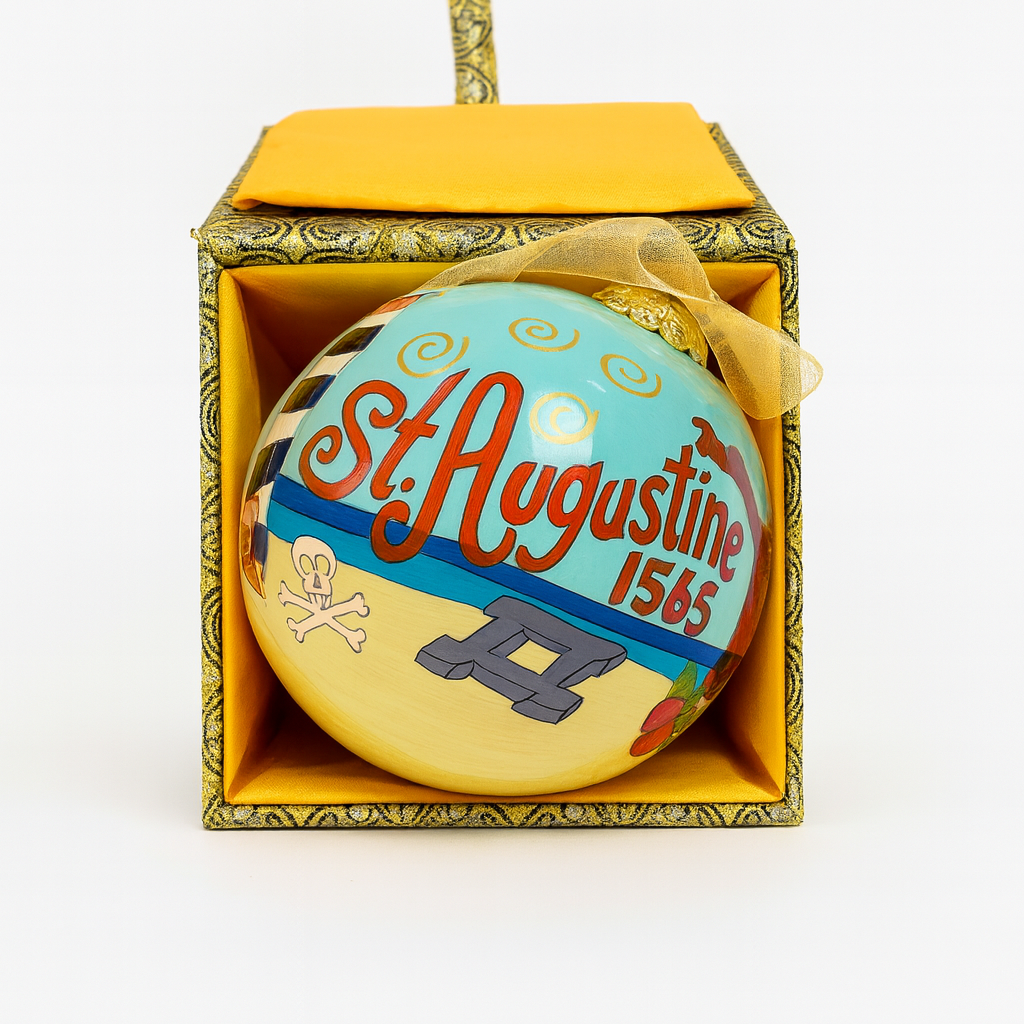 Hand-painted glass Christmas ornament with “St. Augustine 1565” lettering, beach scene artwork, and gold hanging ribbon photographed on a clean white background.