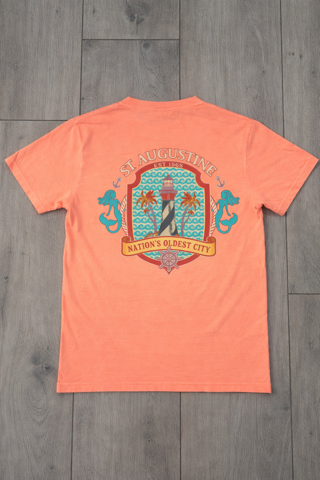 Coral St. Augustine graphic tee featuring a lighthouse, mermaids, and “Nation’s Oldest City” coastal design. A fun Florida souvenir shirt. Available at www.artsyabode.com
or in store at Artsy Abode located in historic downtown St Augustine.