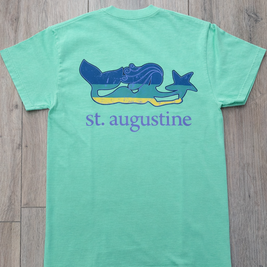 Back of mint green St. Augustine t-shirt with a stylized mermaid tail and starfish graphic above lavender “st. augustine” text.