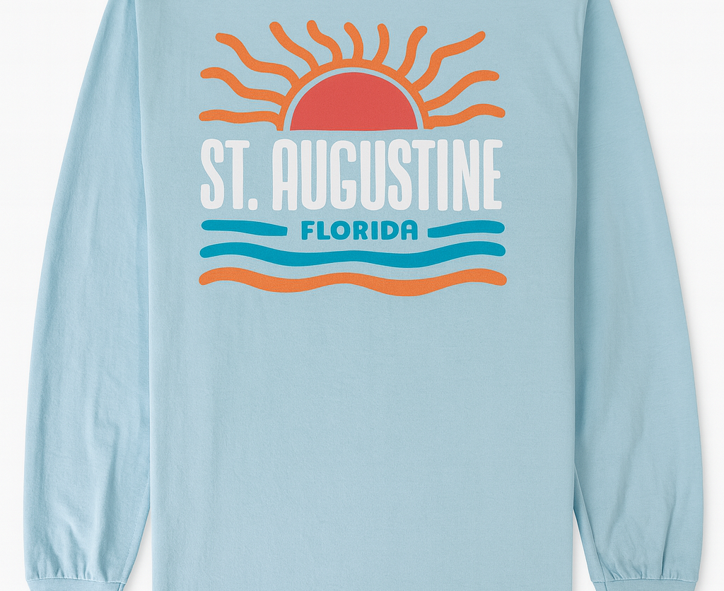 Light blue cotton long sleeve shirt with raised puffy decal design featuring a sunrise, waves, and bold St. Augustine Florida text.