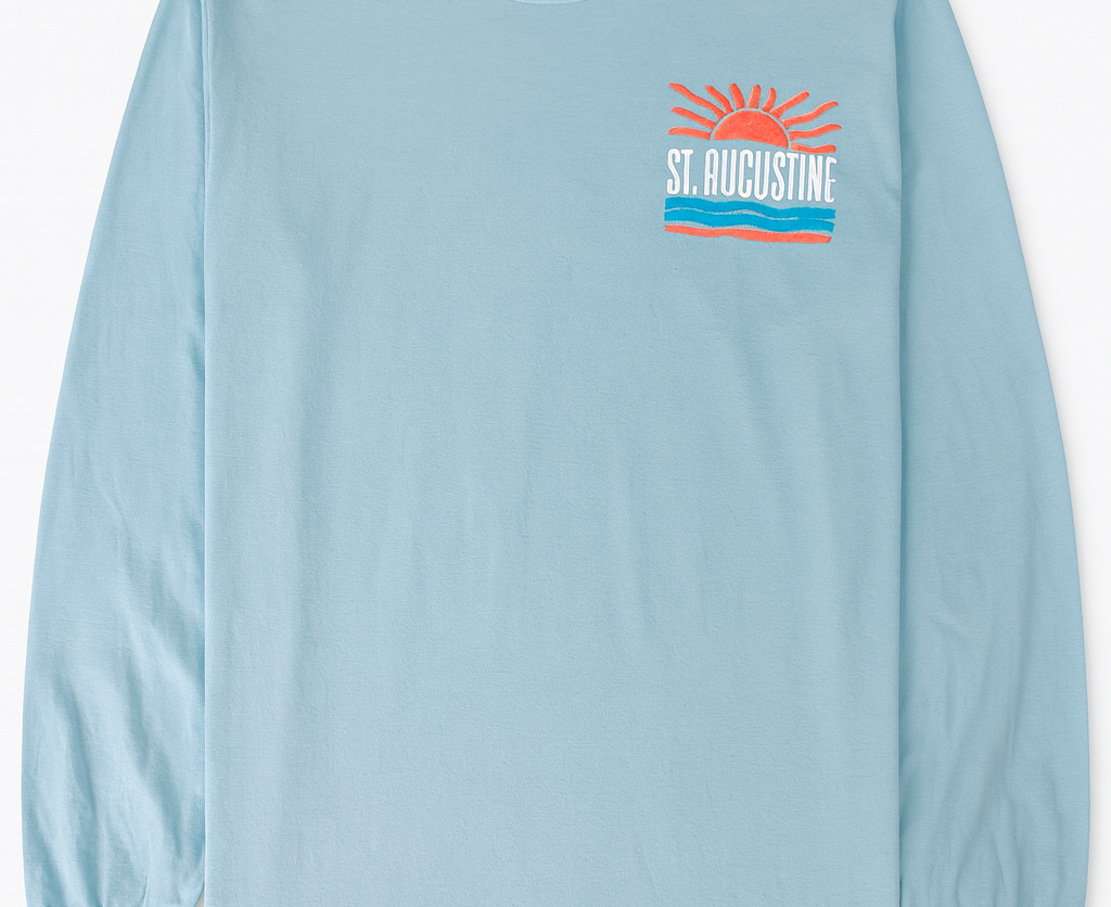 Light blue cotton long sleeve shirt with raised puffy decal design featuring a sunrise, waves, and bold St. Augustine Florida text.