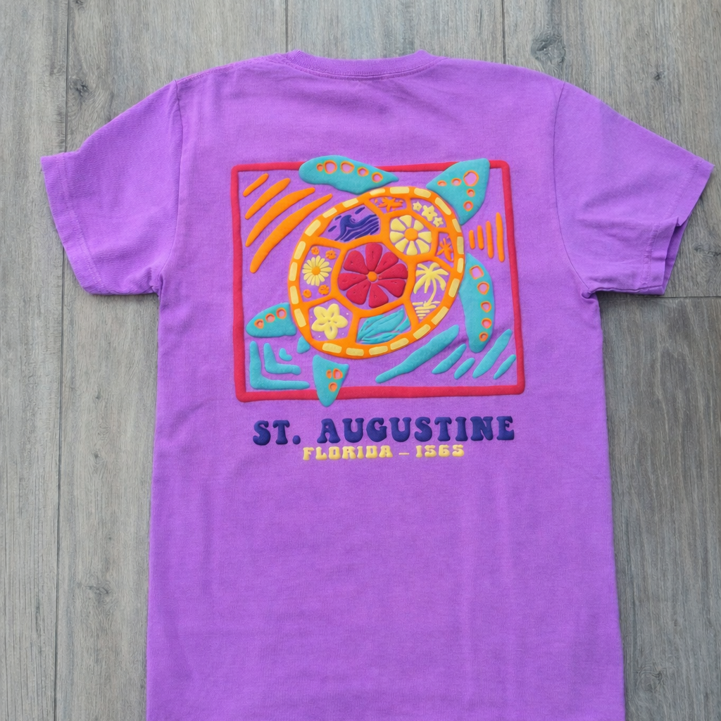 Back of purple St. Augustine t-shirt with colorful sea turtle graphic in a framed design and “St. Augustine Florida - 1565” text.