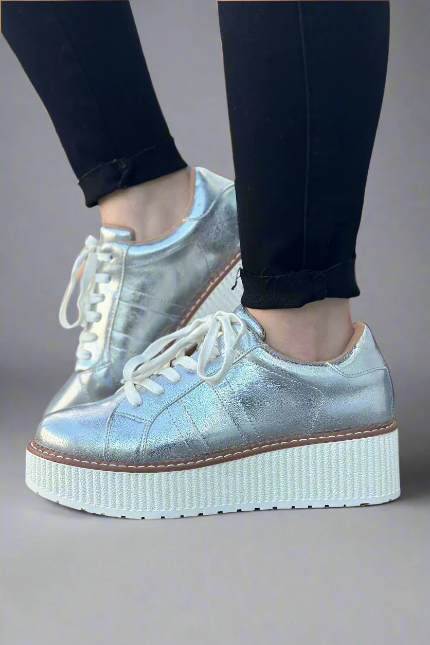 Metallic silver lace-up flatform sneaker with textured white platform sole photographed on a white background.