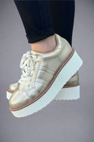 Light gold metallic lace-up flatform sneaker with a textured white platform sole photographed on a white background.