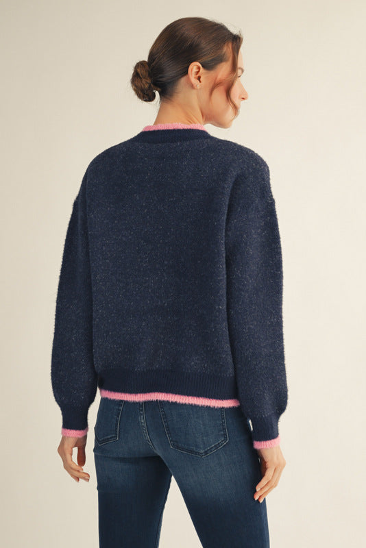 Model wearing a navy Christmas sweater with colorful tree patterns and a sparkling sequin tree in the center, paired with dark blue jeans — festive, cozy, and perfect for the holidays.