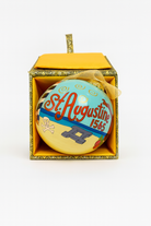 Hand-painted glass Christmas ornament with “St. Augustine 1565” lettering, beach scene artwork, and gold hanging ribbon photographed on a clean white background.