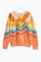 Colorful retro-style St. Augustine crewneck sweatshirt with embroidered text and wavy stripe design in warm sunset tones.
