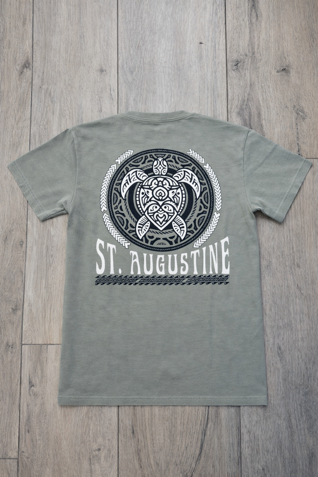 Back of sage green St. Augustine t-shirt with large tribal-style sea turtle graphic and bold white St. Augustine text.