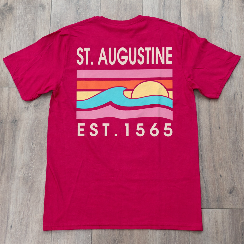 Back of magenta St. Augustine t-shirt with retro sunset stripe graphic, turquoise wave design, and “ST. AUGUSTINE EST. 1565” text.
